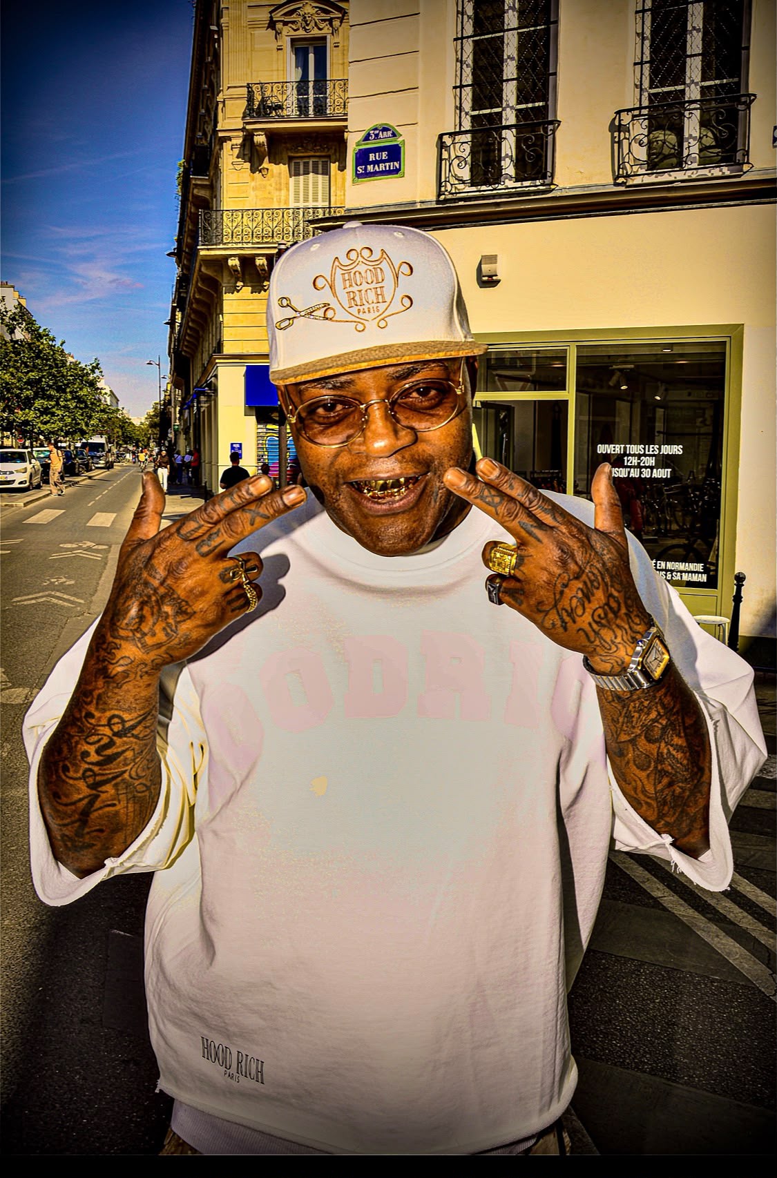 Portrait de rue rue Saint-Martin : homme en casquette blanche et lunettes dorées faisant des gestes de ses mains tatouées